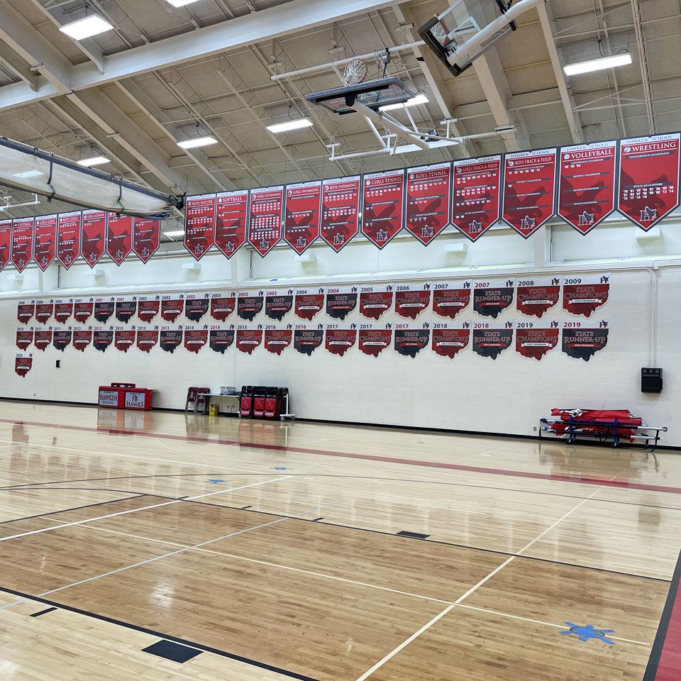 custom add a year banners by SchoolPride® hanging from gym rafters